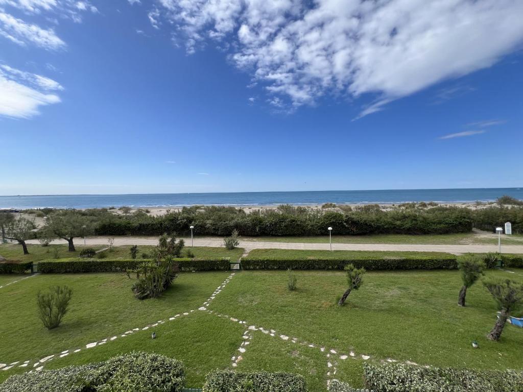 - une vue sur un parc avec l'océan en arrière-plan dans l'établissement Sol-y-Days Escale, appartement en premiere ligne face a la mer, à La Grande Motte