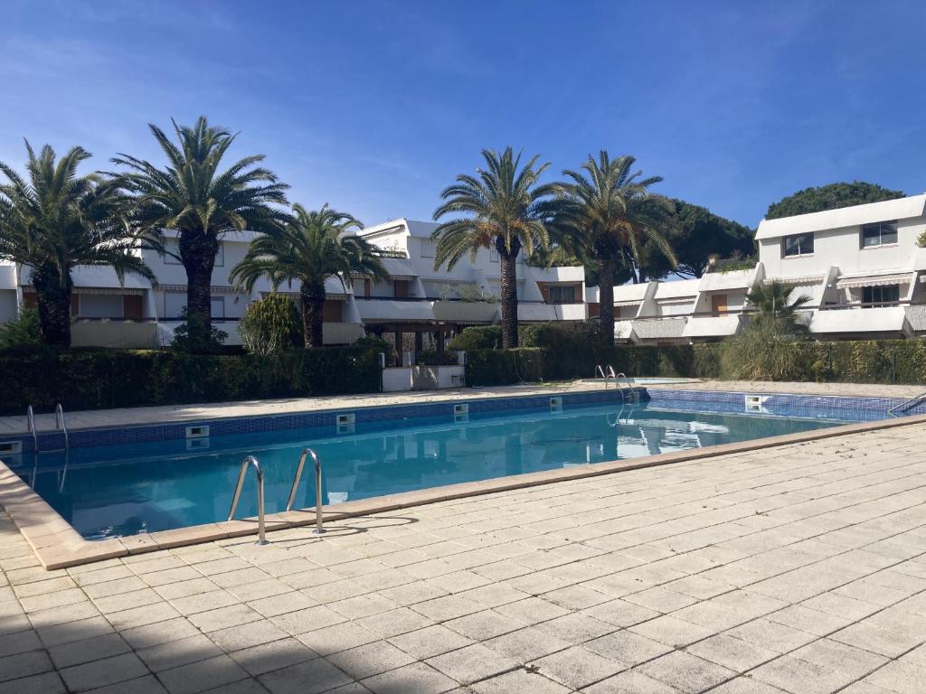 a swimming pool with palm trees in front of a building at Sol-y-Days Cyprianes appartement moderne avec piscine in La Grande-Motte