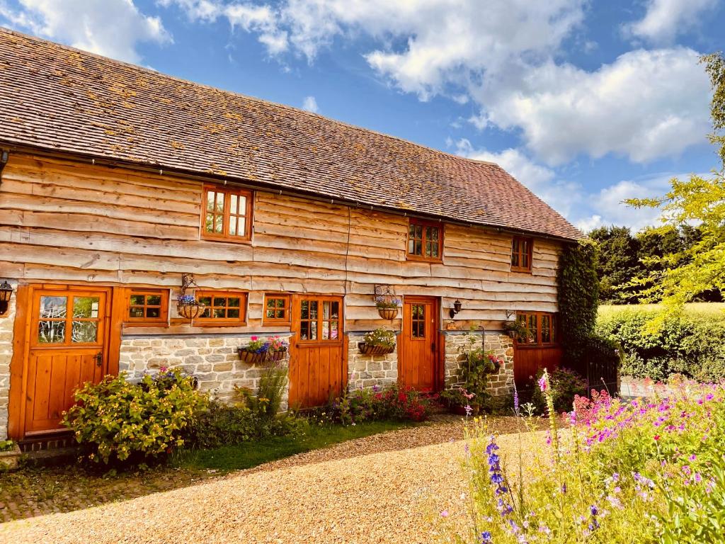 a wooden house with wooden doors and flowers at Tawny Owl Barn in Craven Arms