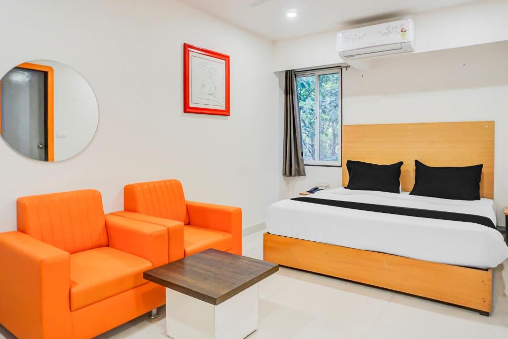 a bedroom with a bed and a chair at Super Townhouse Hadapsar formerly Savali Inn in Pune
