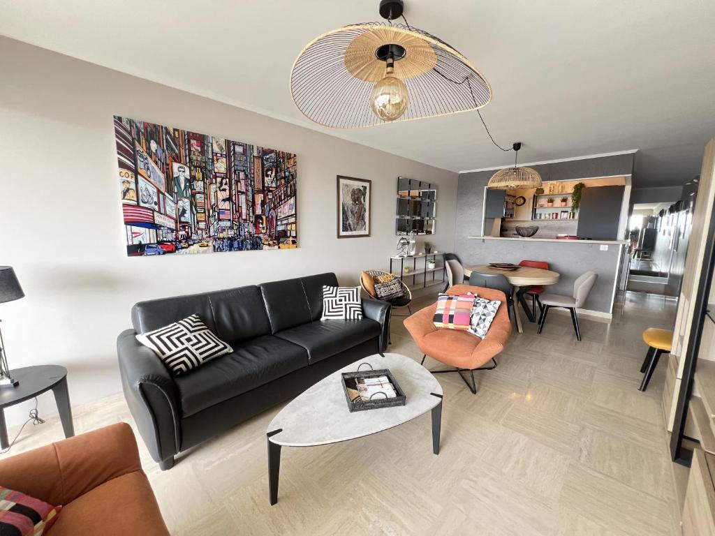 un salon avec un canapé noir et une table dans l'établissement Sol-y-Days Eden, Magnifique appartement de deux chambres, en duplex face a la mer et au port de plaisance, à La Grande Motte