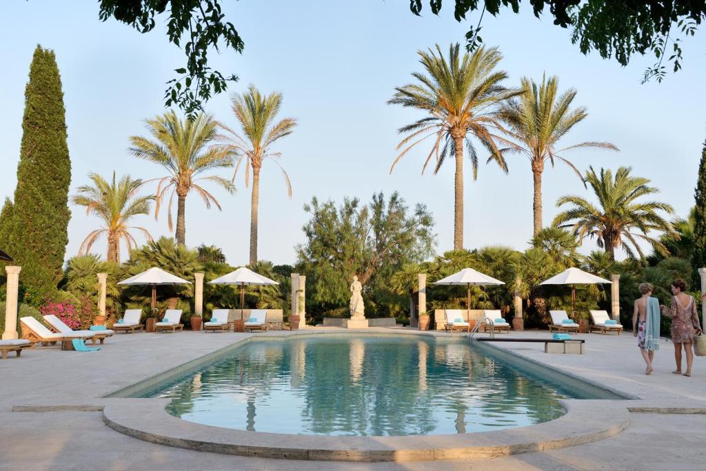 une piscine bordée de palmiers et de personnes debout autour de celle-ci dans l'établissement Cal Reiet Holistic Retreat, à Santanyí