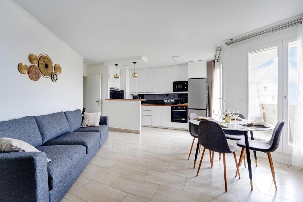 ein Wohnzimmer mit einem blauen Sofa und einem Tisch in der Unterkunft Babylone 2 premium in Le Pré-Saint-Gervais