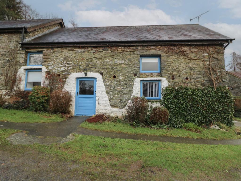 an old stone house with a blue door at Y Beudy in Llanybydder