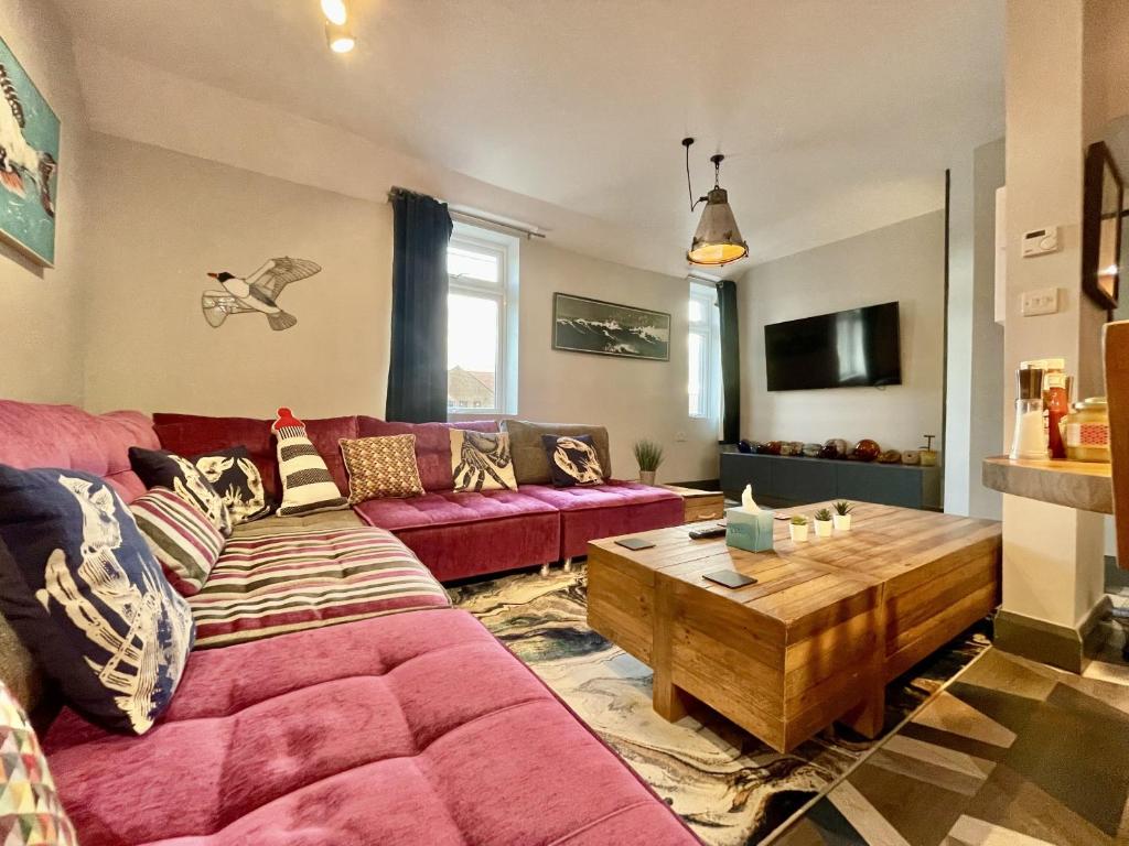 a living room with a red couch and a wooden table at Cod in Seahouses