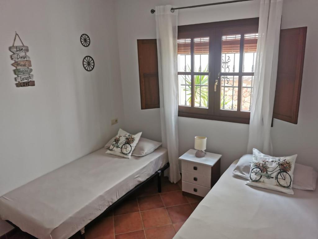 two beds in a room with a window at Apartamento María Platero Céntrico y con las mejores vistas del casco antiguo la montaña y el mar mediterráneo in Frigiliana