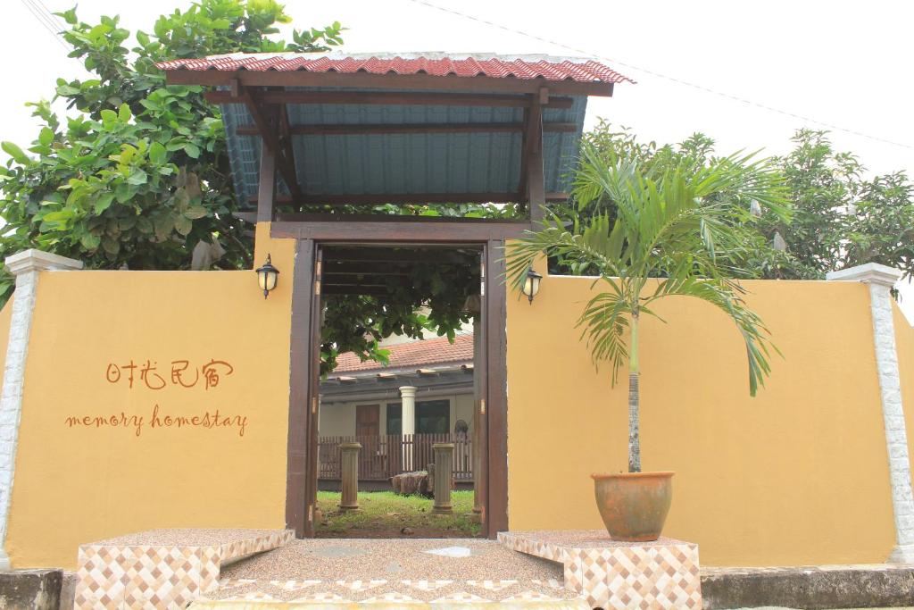 a building with a sign and a potted plant at Memory Homestay in Kampong Baharu