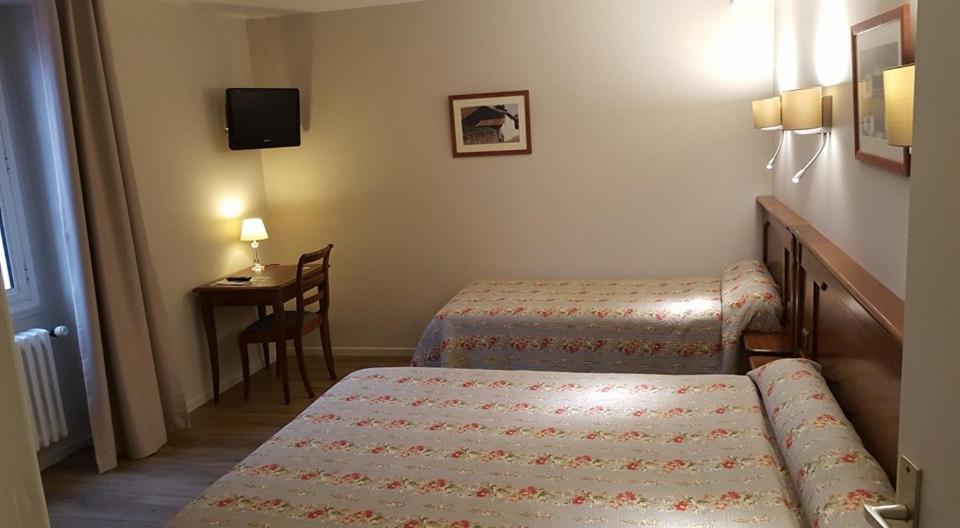 a hotel room with two beds and a table at Hotel Eskualduna Chez Katina in Saint-Martin-dʼArrossa