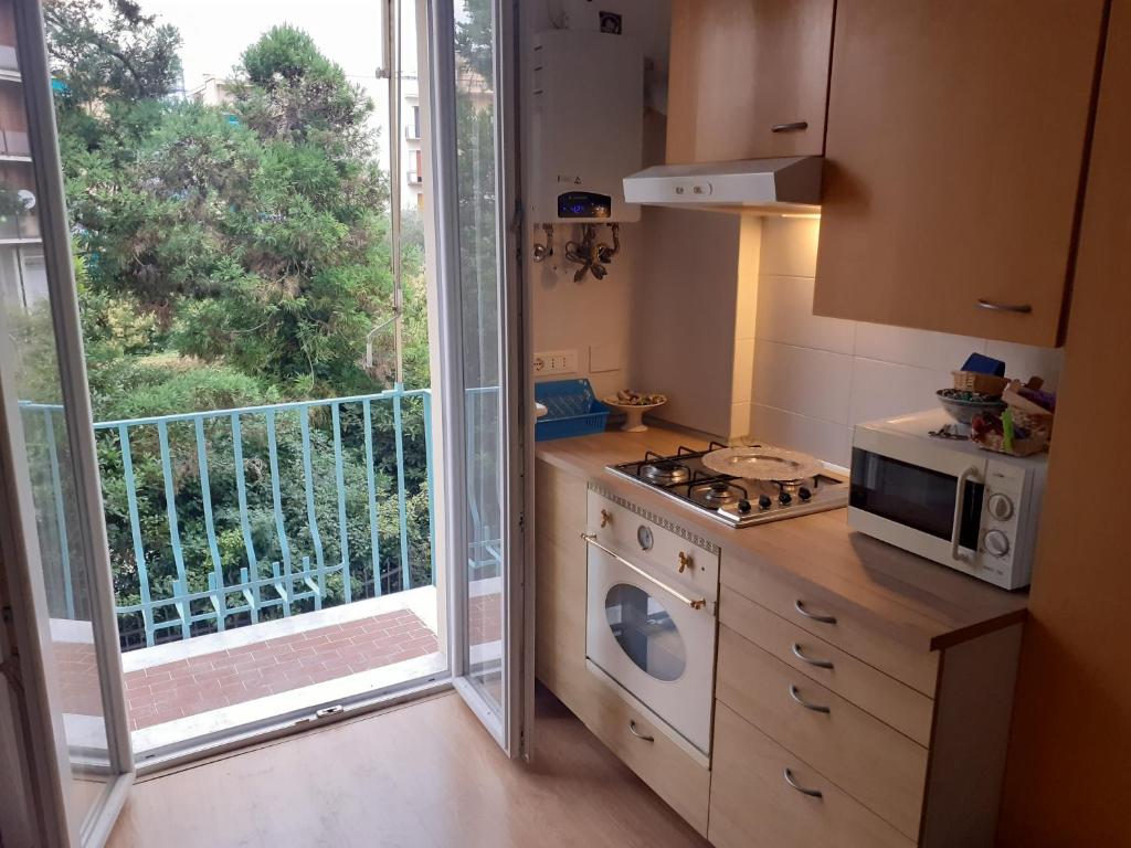 热那亚Casa Lelia, 86 m2, beach, Gaslini的一间带炉灶和微波炉的厨房以及一个阳台