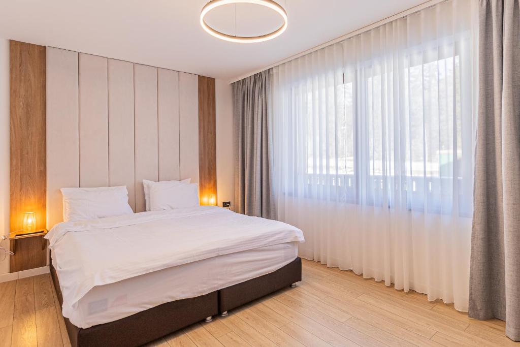ブラショヴにあるALBERT RESIDENCE APARTHOTEL GRAND CHALET with special rate to SPA Alpin Resortの大きなベッドと大きな窓のある寝室