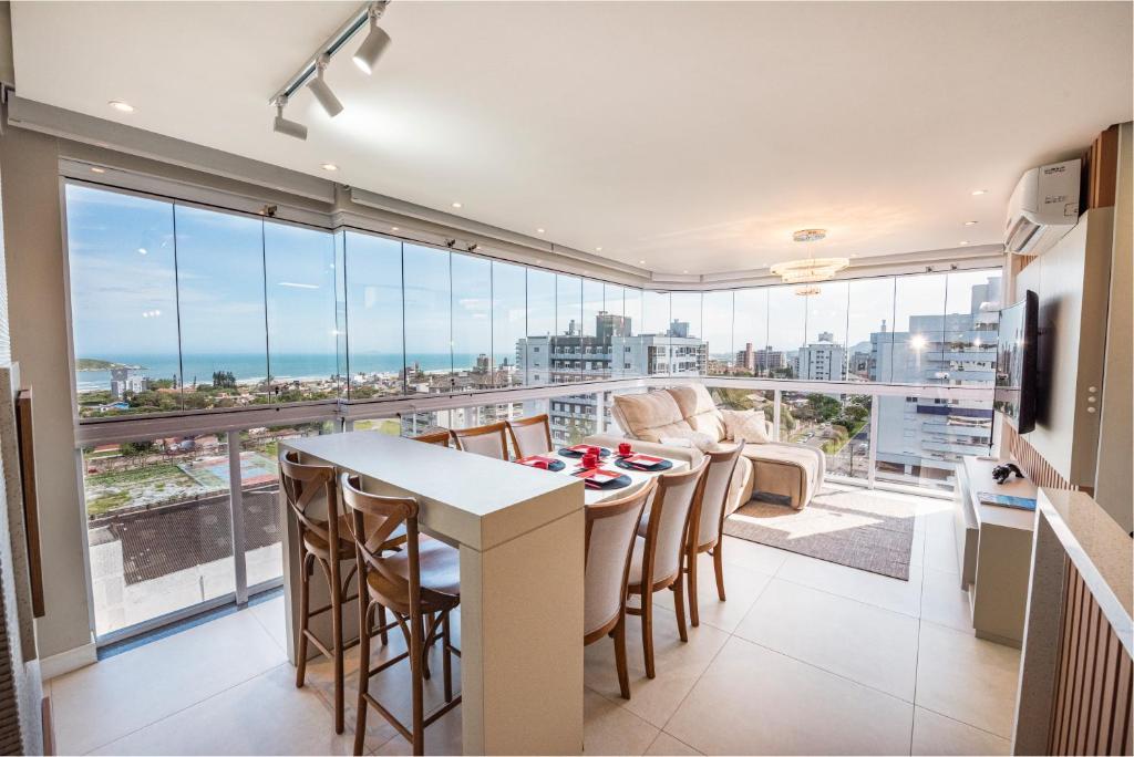 Una sala de estar con una mesa y sillas y una gran ventana. en Cobertura com vista panorâmica da Praia da Vila, en Imbituba
