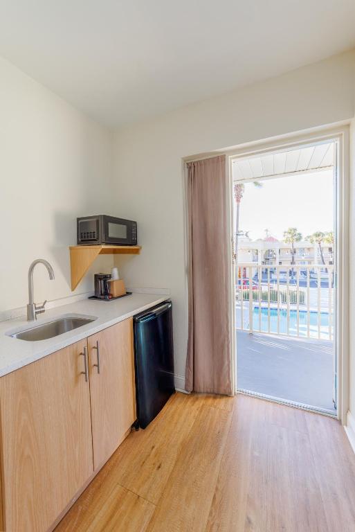 a kitchen with a sink and a door to a balcony at Dunes Inn & Suites - Tybee Island in Tybee Island