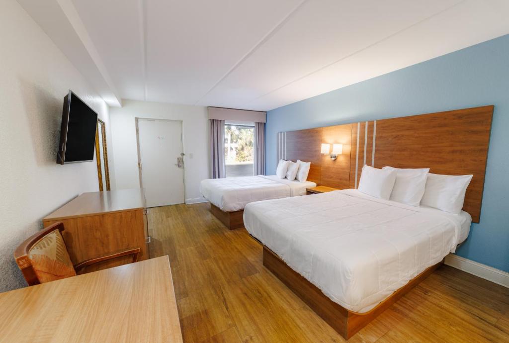 a hotel room with two beds and a television at Dunes Inn & Suites - Tybee Island in Tybee Island