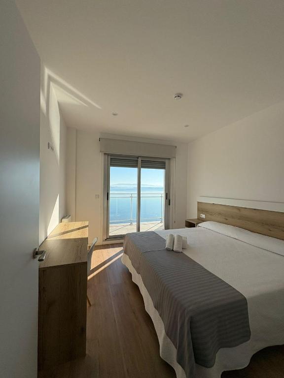 a bedroom with a large bed and a large window at Apartamentos O Grove Awa Bay in O Grove