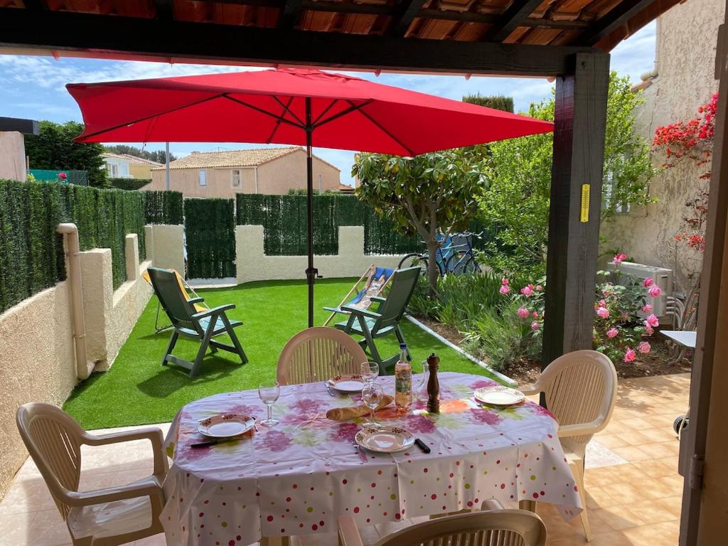 - une table avec un parasol rouge sur la terrasse dans l'établissement Au calme à Sanary, villaT2 climatisée pour 4 pers, à Sanary-sur-Mer