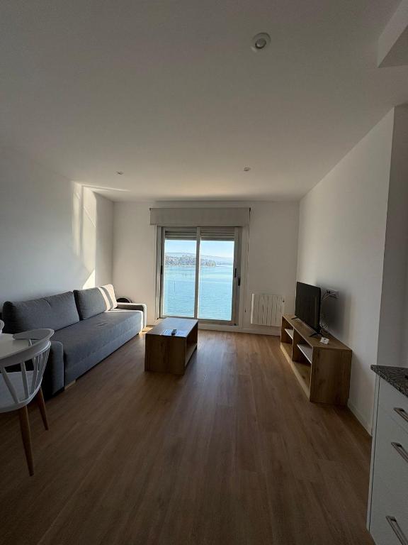 a living room with a blue couch and a television at Apartamentos O Grove Awa Bay in O Grove