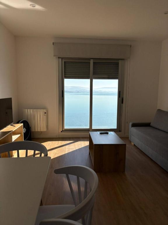 a living room with a couch and a large window at Apartamentos O Grove Awa Bay in O Grove