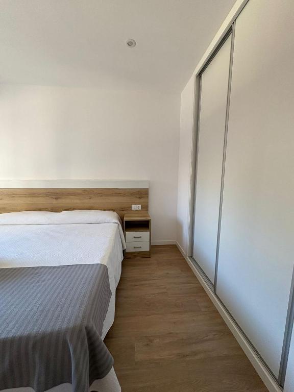a bedroom with two beds and a sliding glass door at Apartamentos O Grove Awa Bay in O Grove