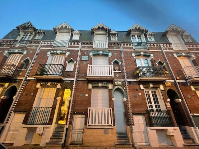 un grand bâtiment en briques avec des fenêtres et des balcons. dans l'établissement La Pintade, au Tréport