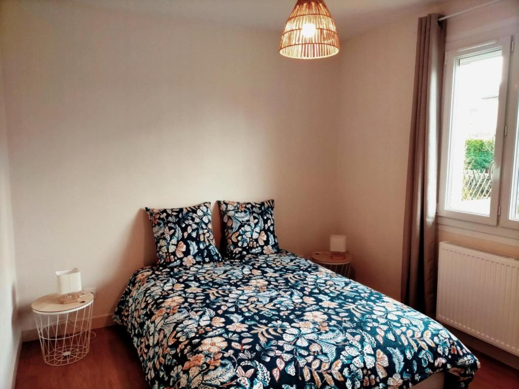 1 Schlafzimmer mit einem Bett mit einer Blumendecke und einem Fenster in der Unterkunft L'étape Nuitonne - Gîte avec jardin pour 6 personnes in Nuits-Saint-Georges