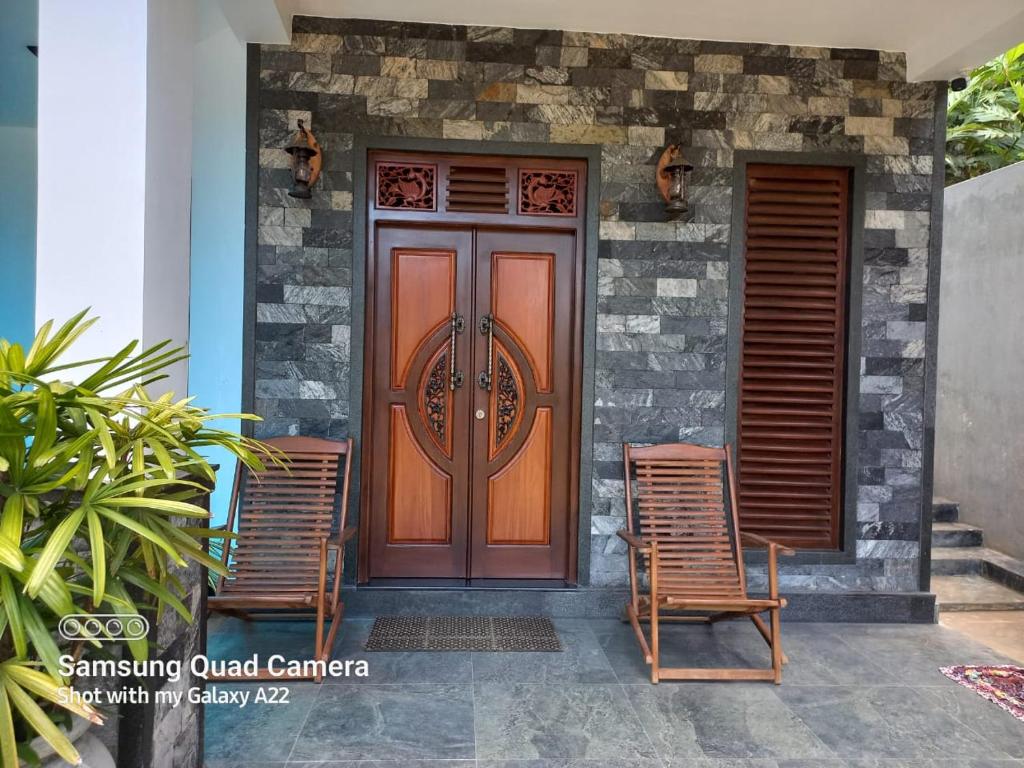 a wooden door with two chairs in front of a house at Villa Meghana in Galle