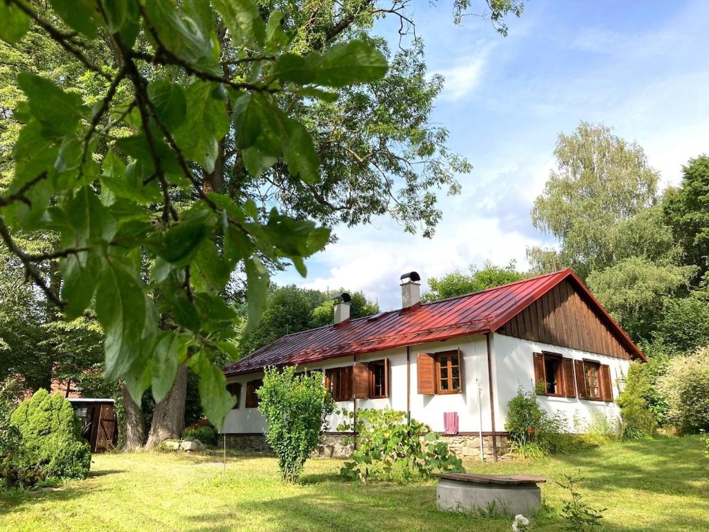 een klein wit huis met een rood dak bij Dvůr Metlice in Rožmberk nad Vltavou