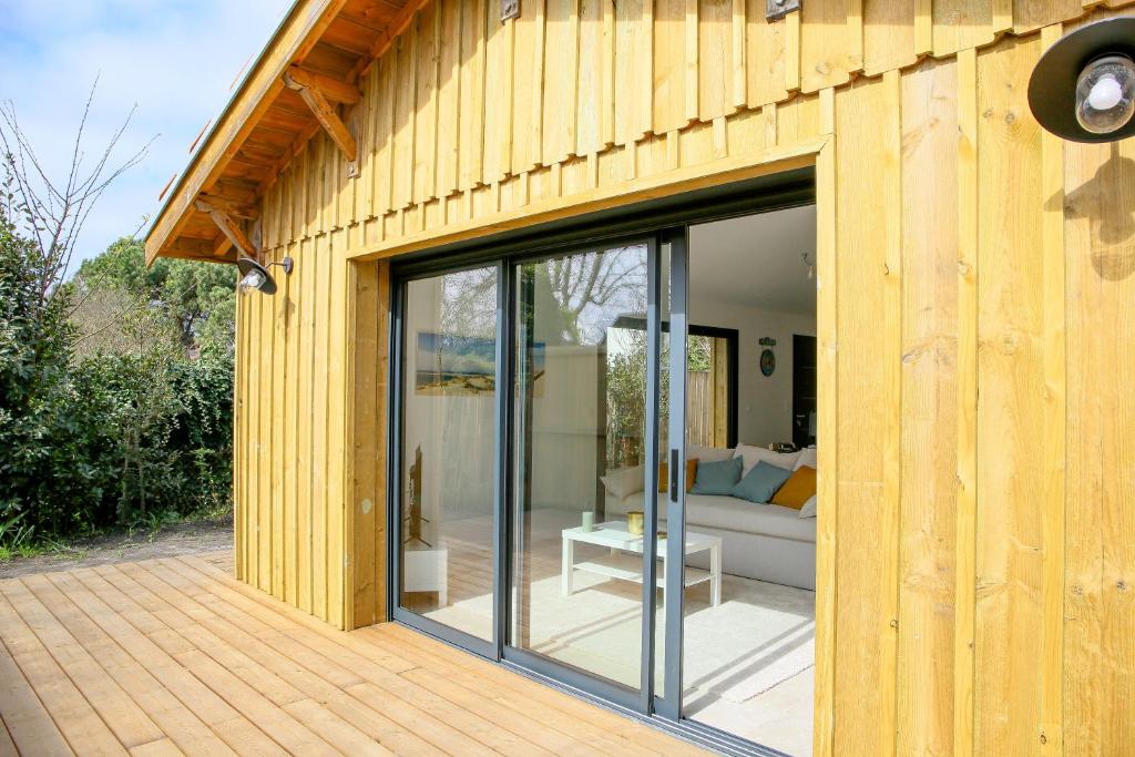 une maison en bois avec des portes coulissantes en verre sur une terrasse dans l'établissement Villa MACAO, à Gujan-Mestras