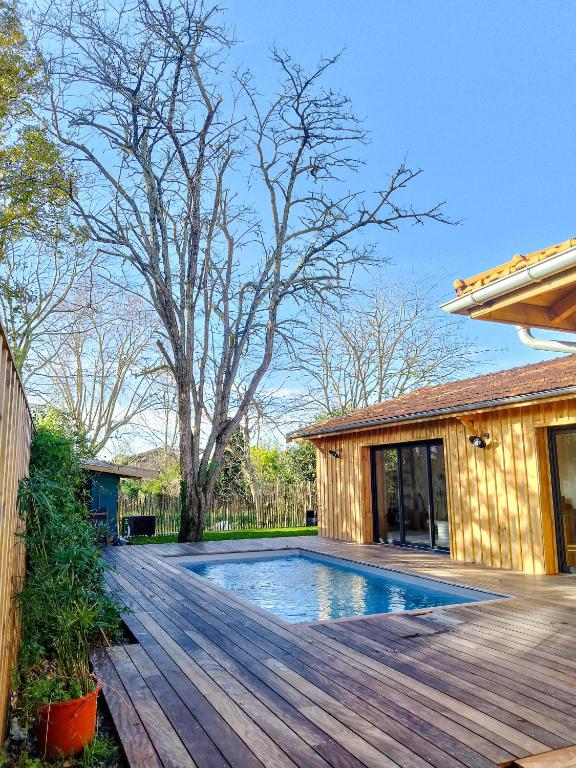 une maison avec une piscine sur une terrasse en bois dans l'établissement Villa Onébien, à Gujan-Mestras