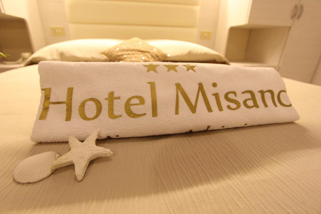 una toalla de hotel mitziana en una cama con estrella de mar en Hotel Misano, en Misano Adriatico