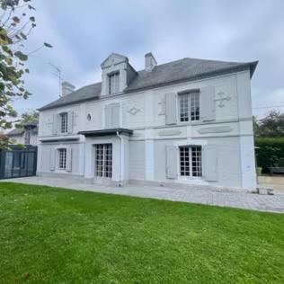 une grande maison blanche avec une pelouse verte dans l'établissement Le Presbytère Normand, à Canapville