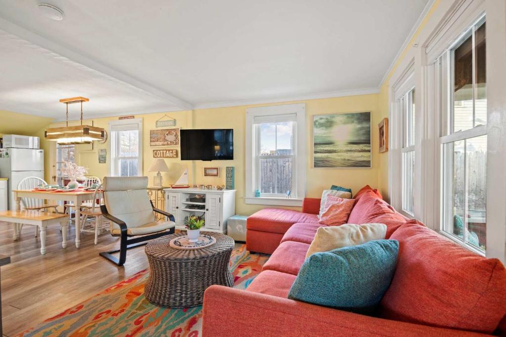 a living room with a red couch and a kitchen at Walk to Private Bayside Beach in Brewster