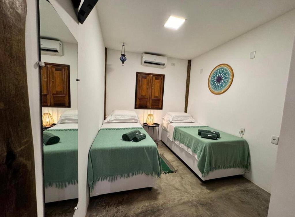 Zimmer mit 2 Betten, grüner Bettwäsche und einem Spiegel in der Unterkunft Noronha Pura Vida in Fernando de Noronha