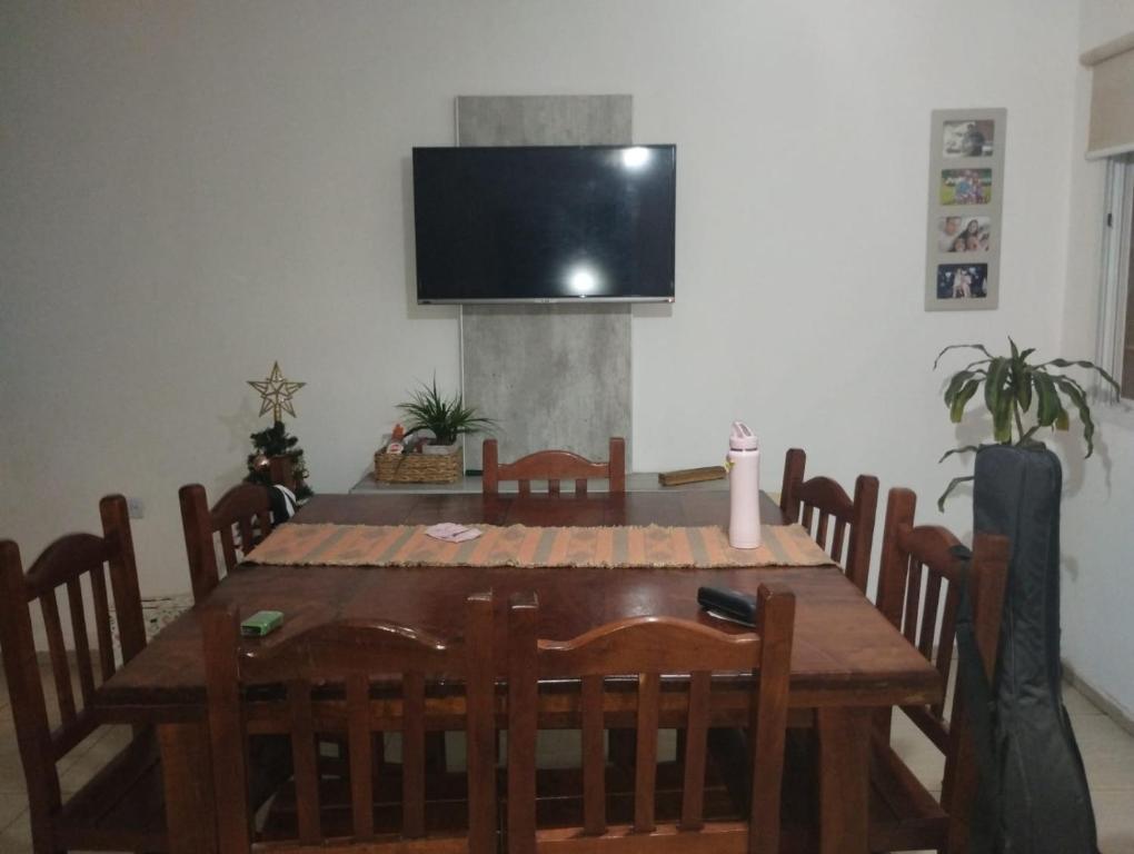 mesa de comedor con sillas y TV en la pared en Casa con pileta, en La Rioja