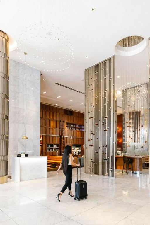 a woman walking through a hotel lobby with a suitcase at Sheraton Grand Los Angeles in Los Angeles