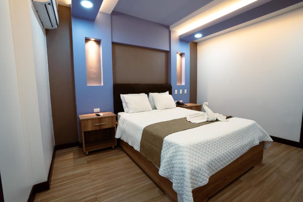 a bedroom with a large bed and a blue wall at Hotel Cayuga in Puntarenas