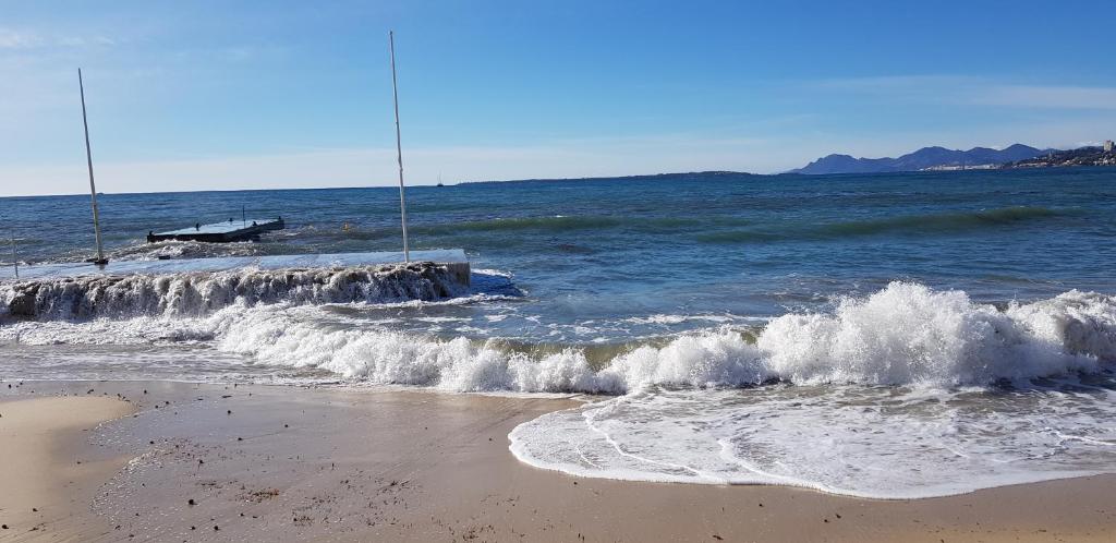 une plage avec des vagues s'écrasant sur la côte dans l'établissement Appartement T2 climatisé à proximite immediate des plages de juan les Pins, à Juan-les-Pins