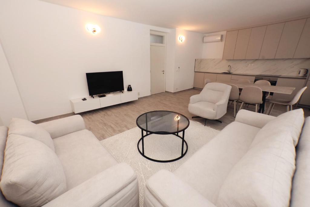 a living room with a white couch and a television at Livinn Apartments-Deluxe Apartment in Prizren