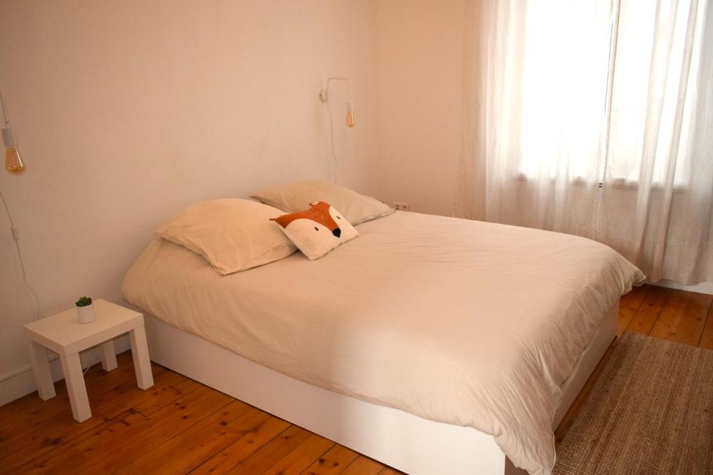 - une chambre dotée d'un lit blanc avec un animal rembourré dans l'établissement Appartement à 10 min de Paris - Train, Métro, à Noisy-le-Sec