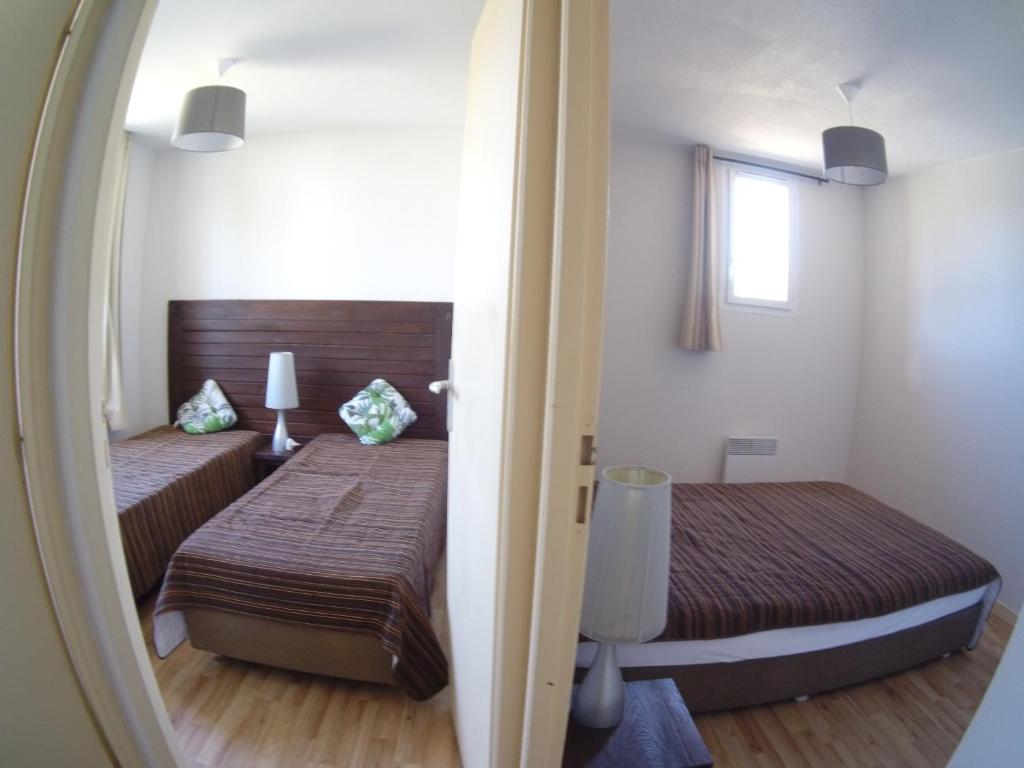 een kleine slaapkamer met twee bedden en een spiegel bij La Pointe du Soleil in Le Verdon-sur-Mer
