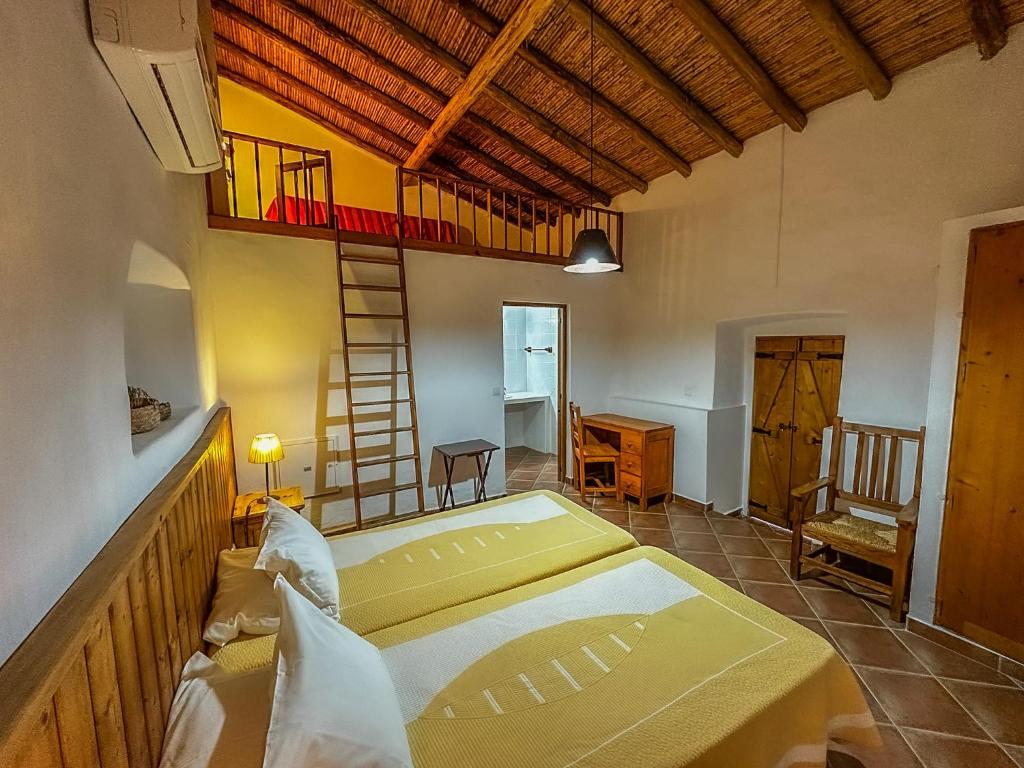 a large room with a bed and a ladder at Casas do Palheiro Velho in Castro Marim
