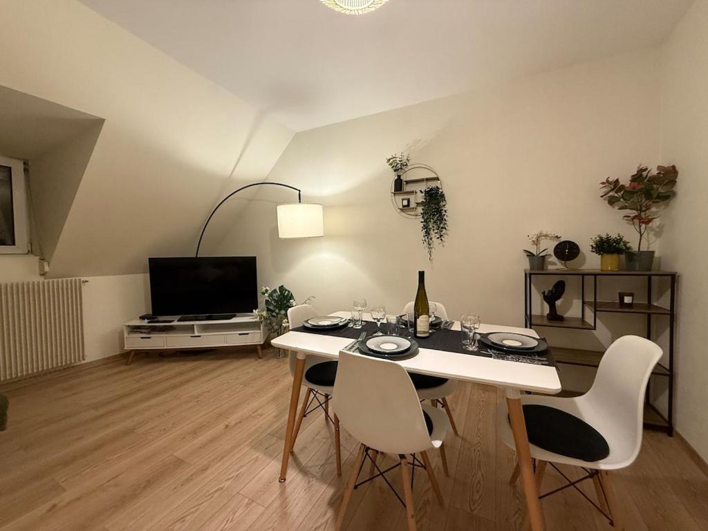 un salon avec une table, des chaises et une télévision dans l'établissement Appartement proche centre ville avec parking, à Colmar