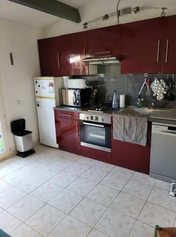 une cuisine avec des armoires rouges et un réfrigérateur blanc dans l'établissement Beija Flor, au Cap d'Agde