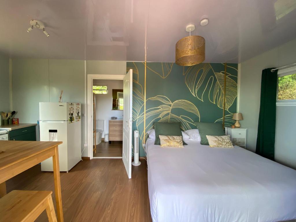a bedroom with a white bed and a green wall at Fare Maraea in Moorea