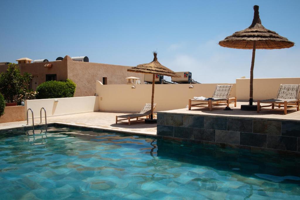 - une piscine avec 2 chaises longues et des parasols dans l'établissement Argan Oasis Studio, Poolside Retreat near Taghazout, à Ikouzza