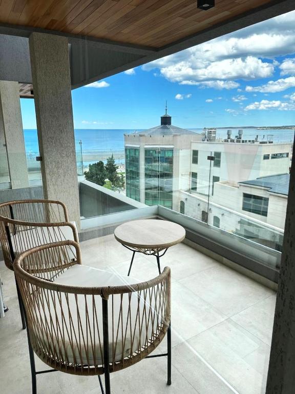 Un balcón con mesa y sillas y vista al mar. en Caleta Centro Madryn, en Puerto Madryn