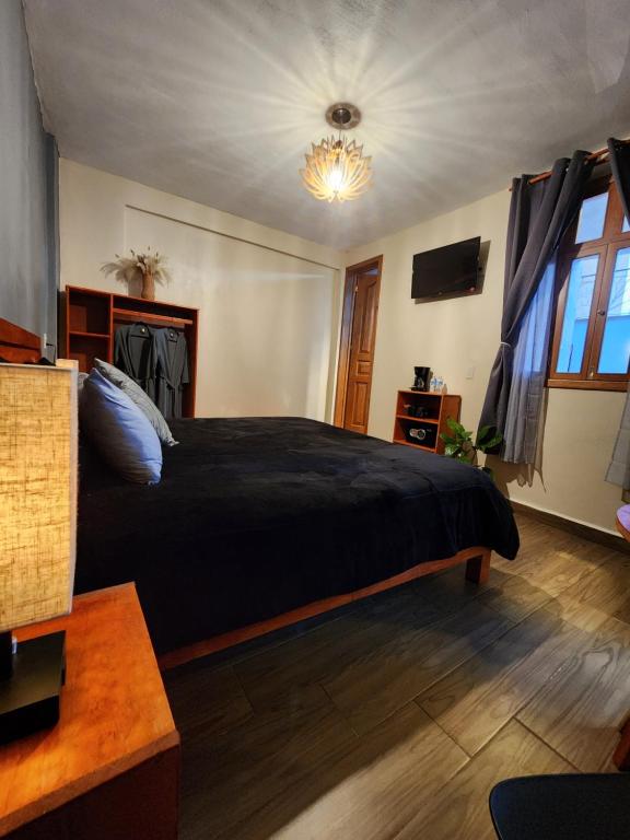 ein Schlafzimmer mit einem schwarzen Bett und einem Kronleuchter in der Unterkunft Piedra Negra Boutique Hotel in San Cristóbal de las Casas