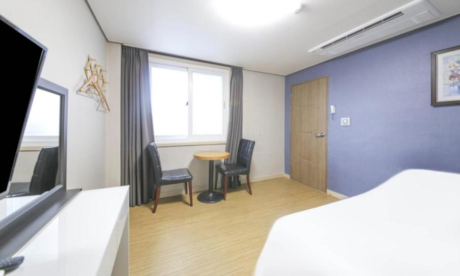 a room with a bed and a table and chairs at Jeju Orastay Hotel in Jeju