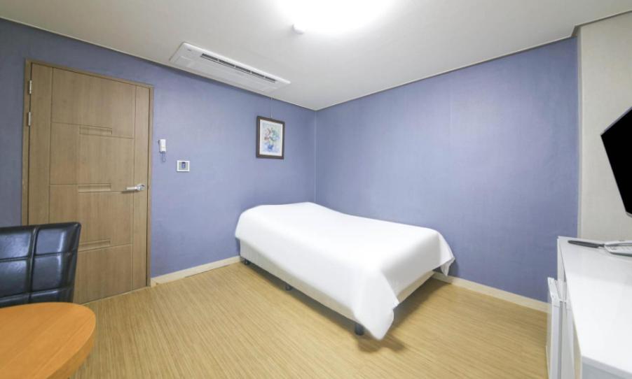 a room with a white bed and a blue wall at Jeju Orastay Hotel in Jeju