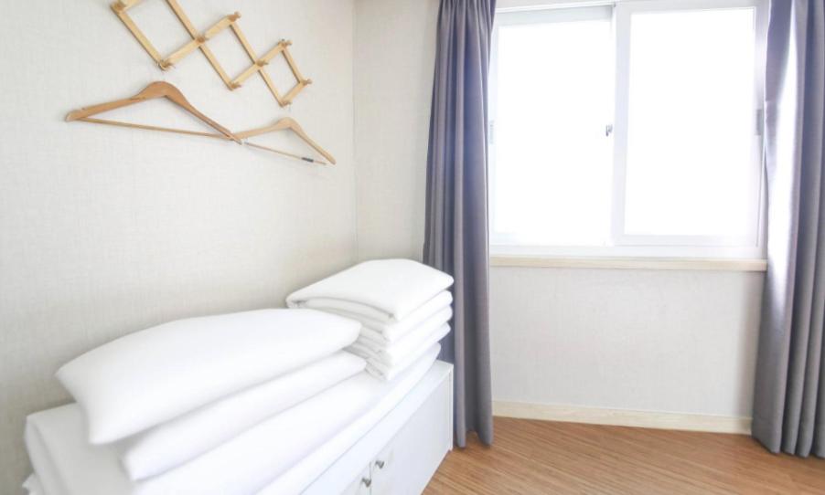 a room with white walls and a window with hangers at Jeju Orastay Hotel in Jeju