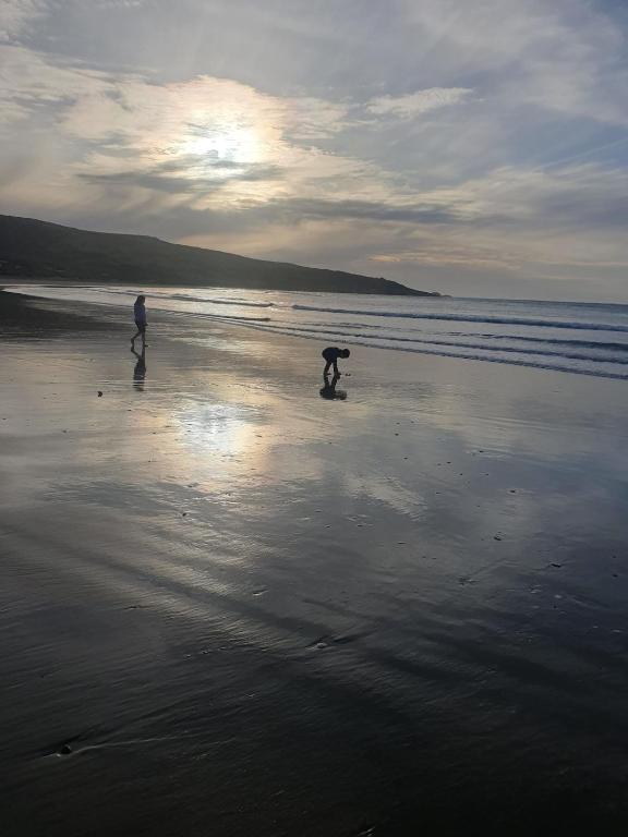 two people are walking on the beach at Peaceful beachside guest house in Invercargill